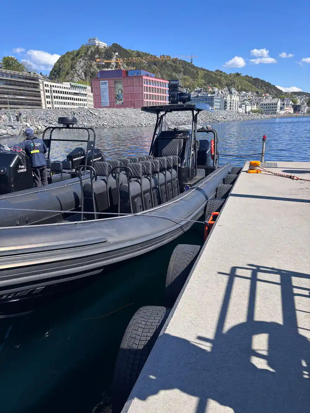 Black speedboat moored at dock with coastal town