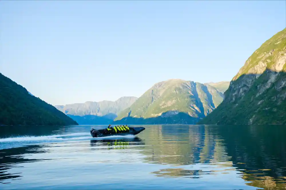 Black speedboat with passengers on reflective blue alpine lake