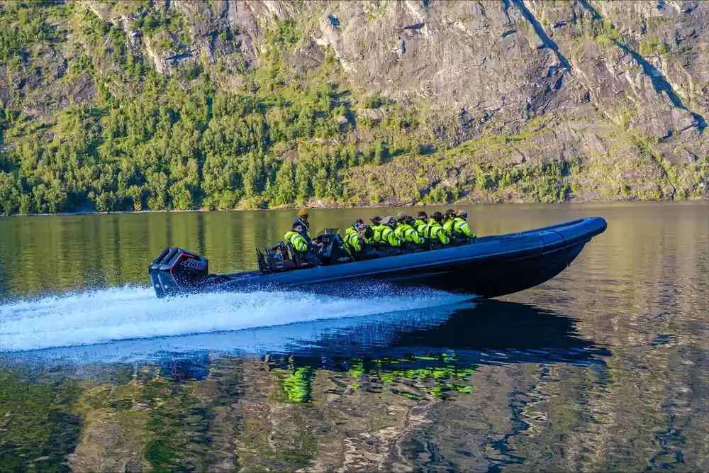 Black speedboat with passengers in yellow vests on blue water