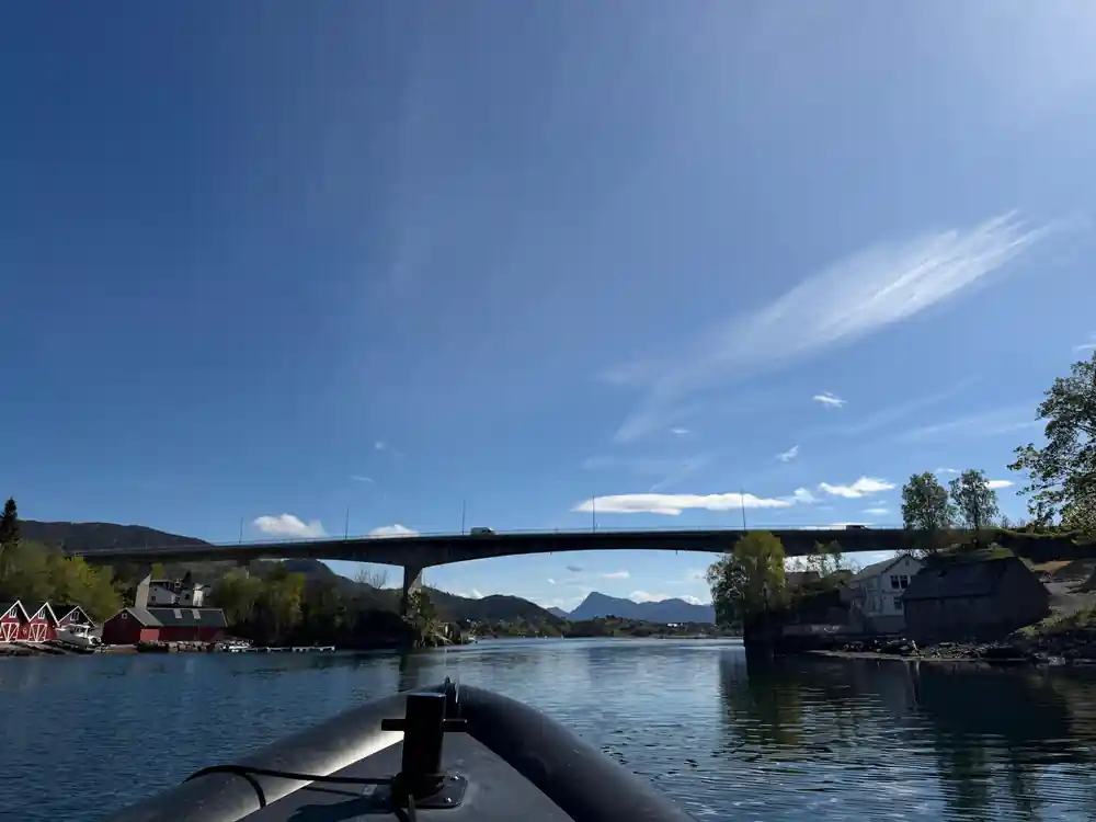Bridge spanning river with mountains and red buildings visible