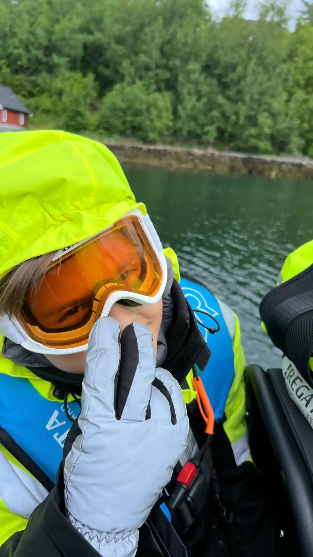 Close-up of person wearing orange ski goggles and white gloves