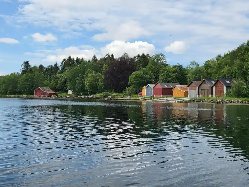 Colorful boathouses reflected in calm blue lake water
