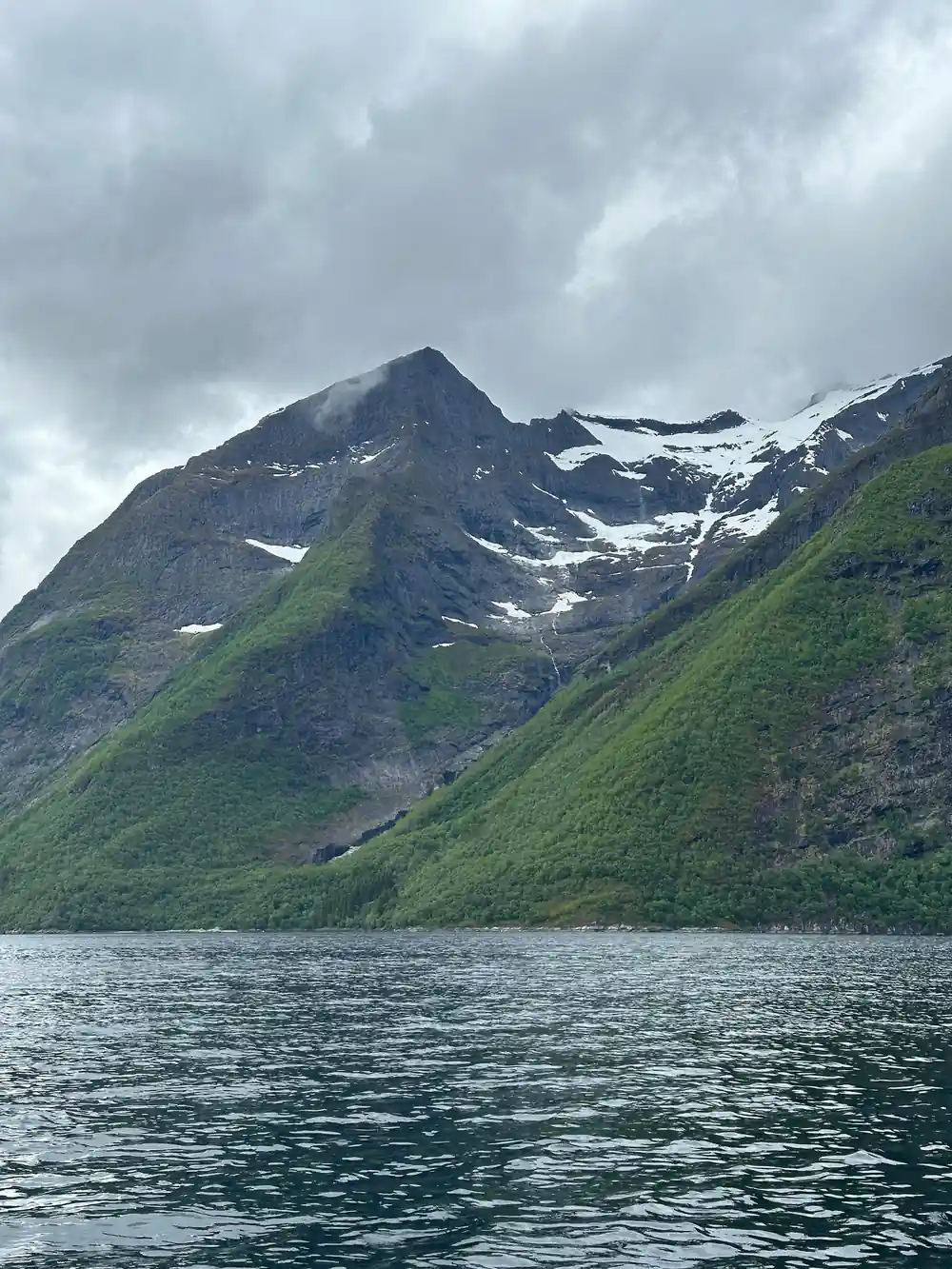 Green mountainside with snow and waterfall