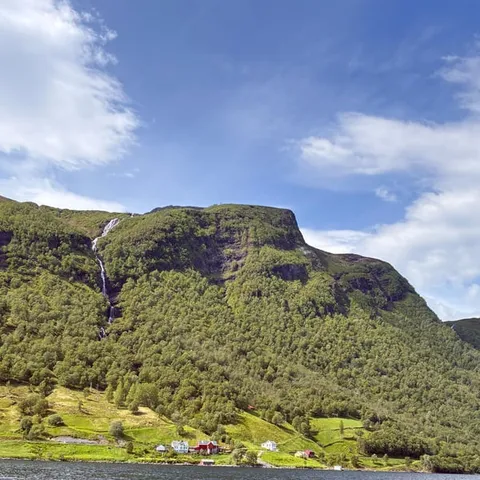 Farms and waterfalls on the green slopes of the Hjørundfjord