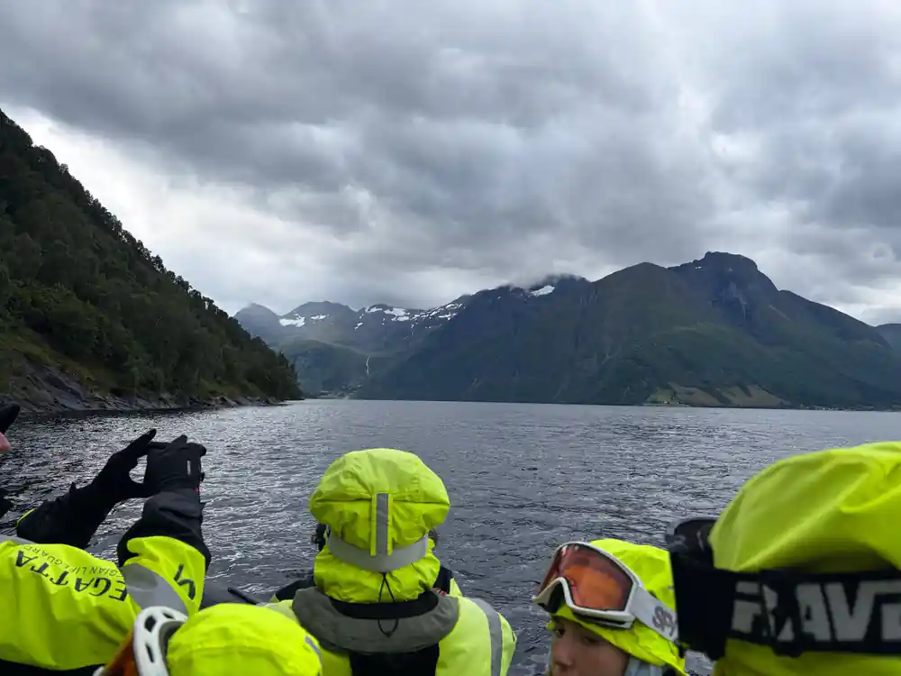 Inflatable boat with passengers and green mountainous fjord