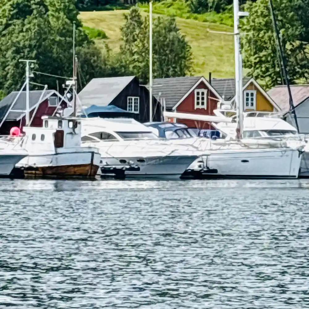 Moored sailboats and cabin cruiser beside waterfront houses
