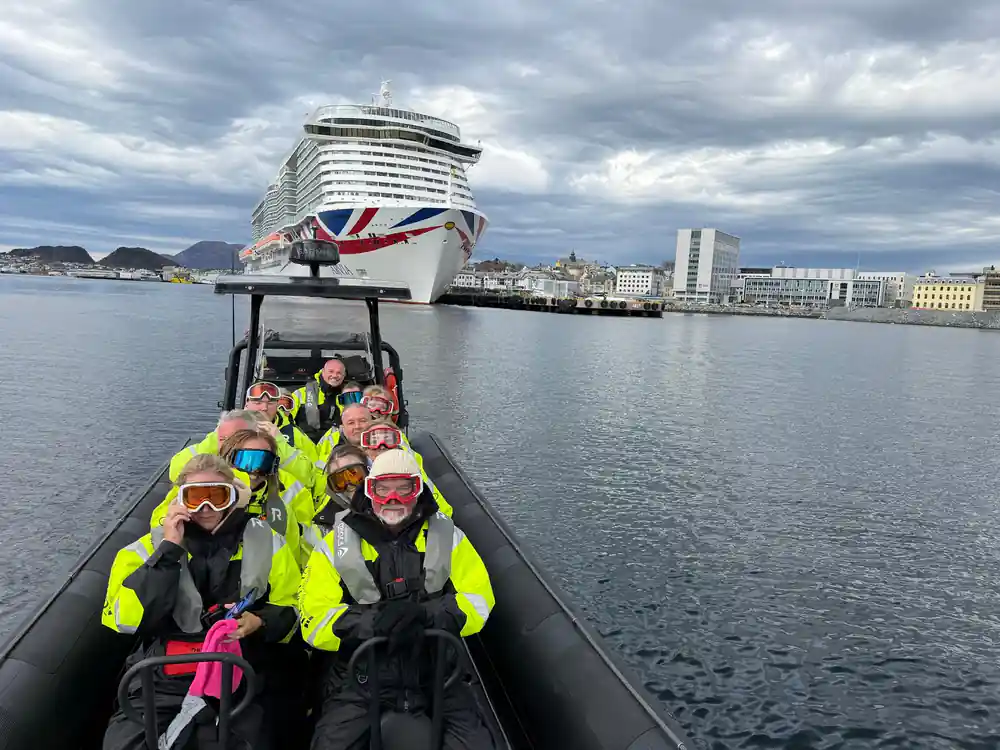 Passengers on speedboat with large cruise ship behind
