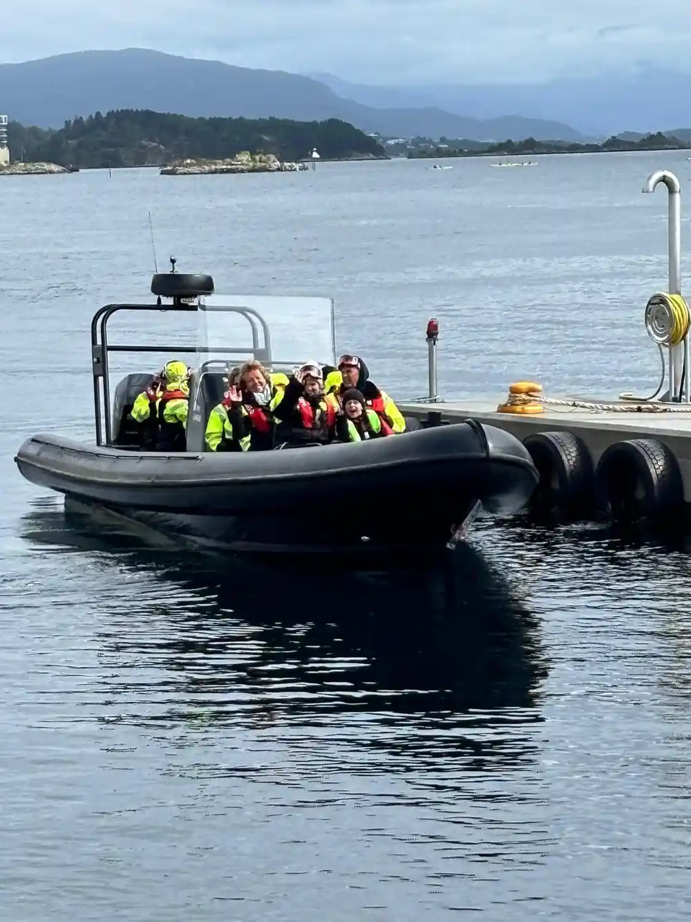 People in life jackets on speedboat near mountains