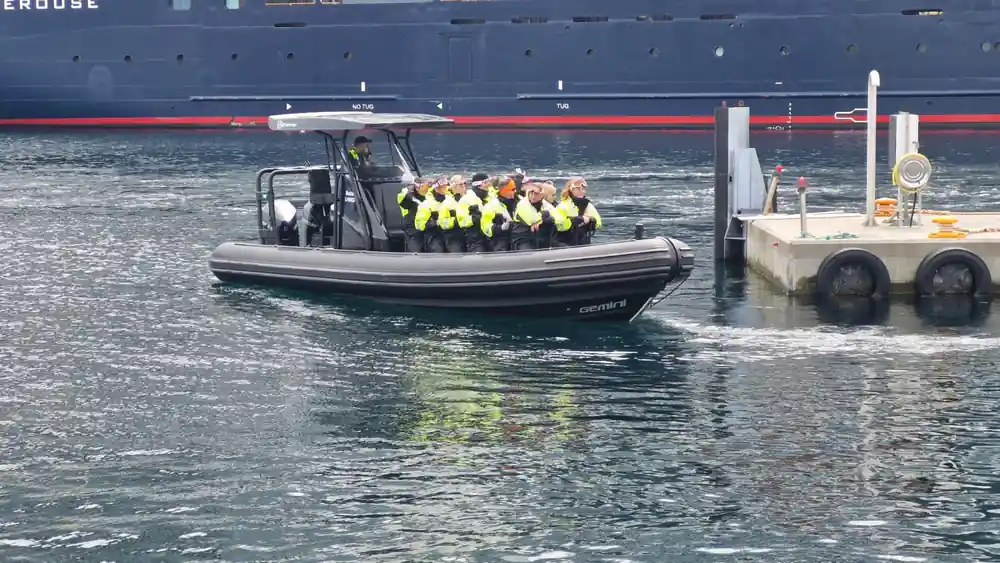 Person in black wetsuit and yellow vest at waterfront viewpoint