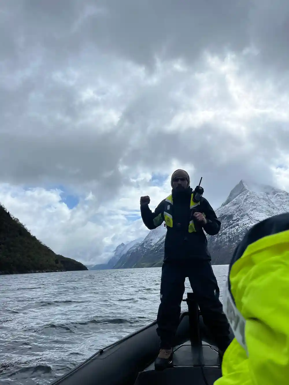 Person in diving suit on boat in mountain fjord