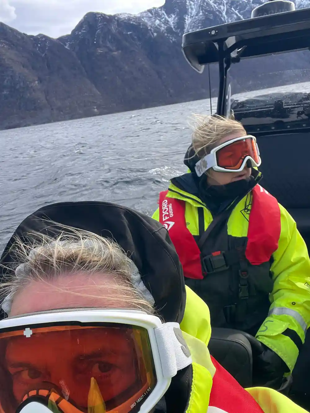 Person in ski goggles on speedboat with mountains