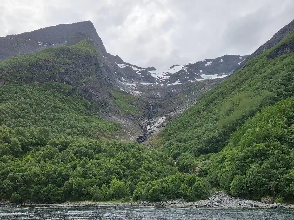 Rocky valley with glacier between steep forested mountainsides