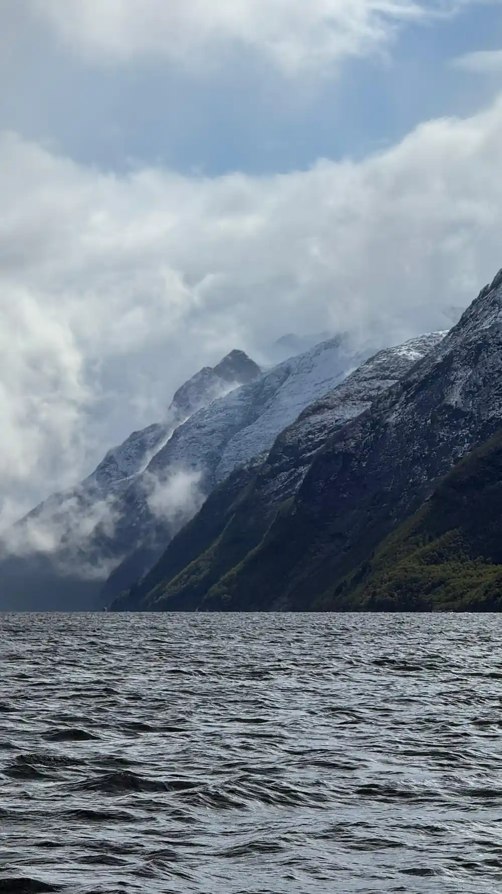 Snow-capped mountain peaks across still water