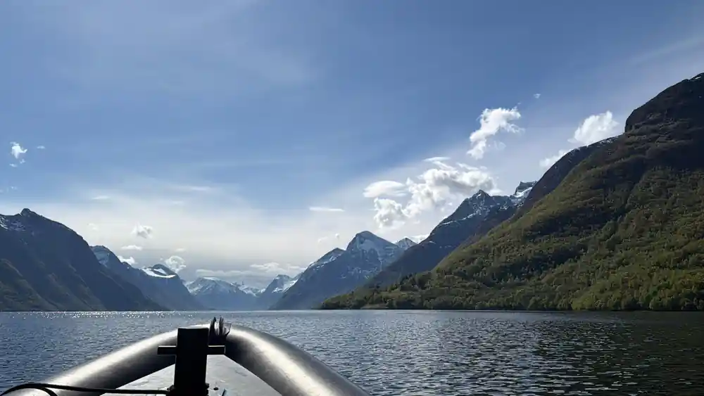Snow-capped mountains reflected in still blue fjord water