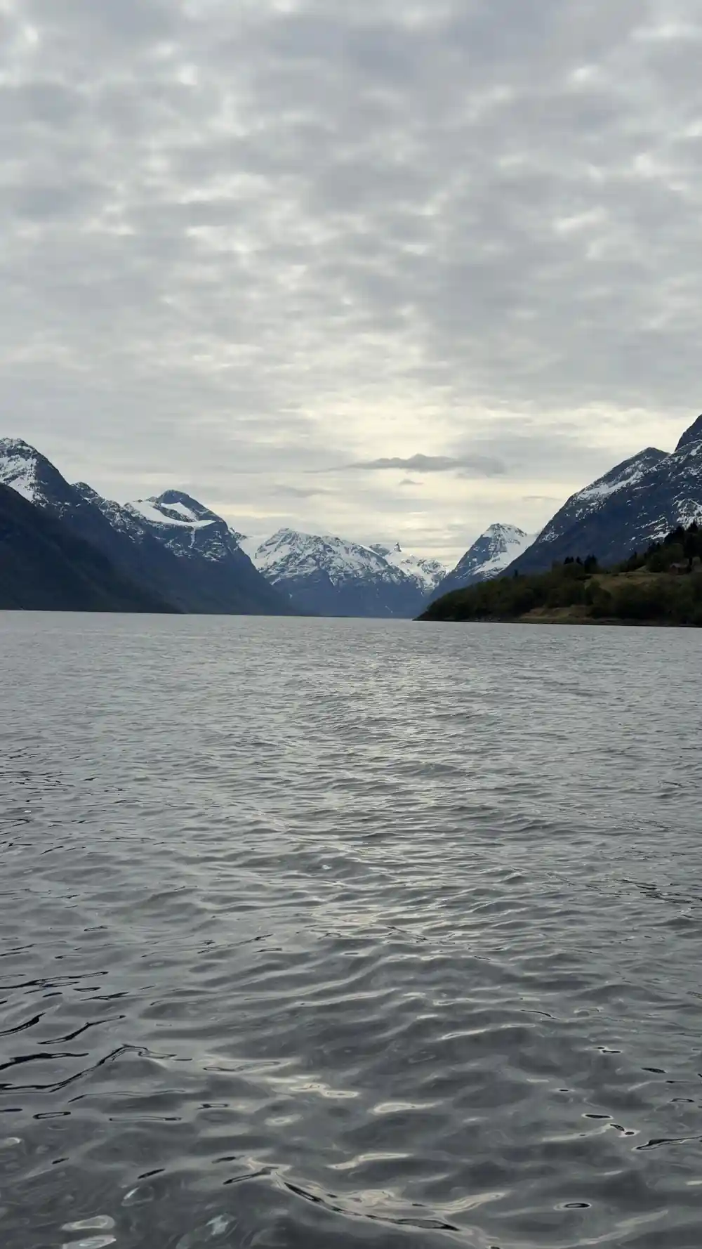 Snow-topped mountains framing calm fjord water
