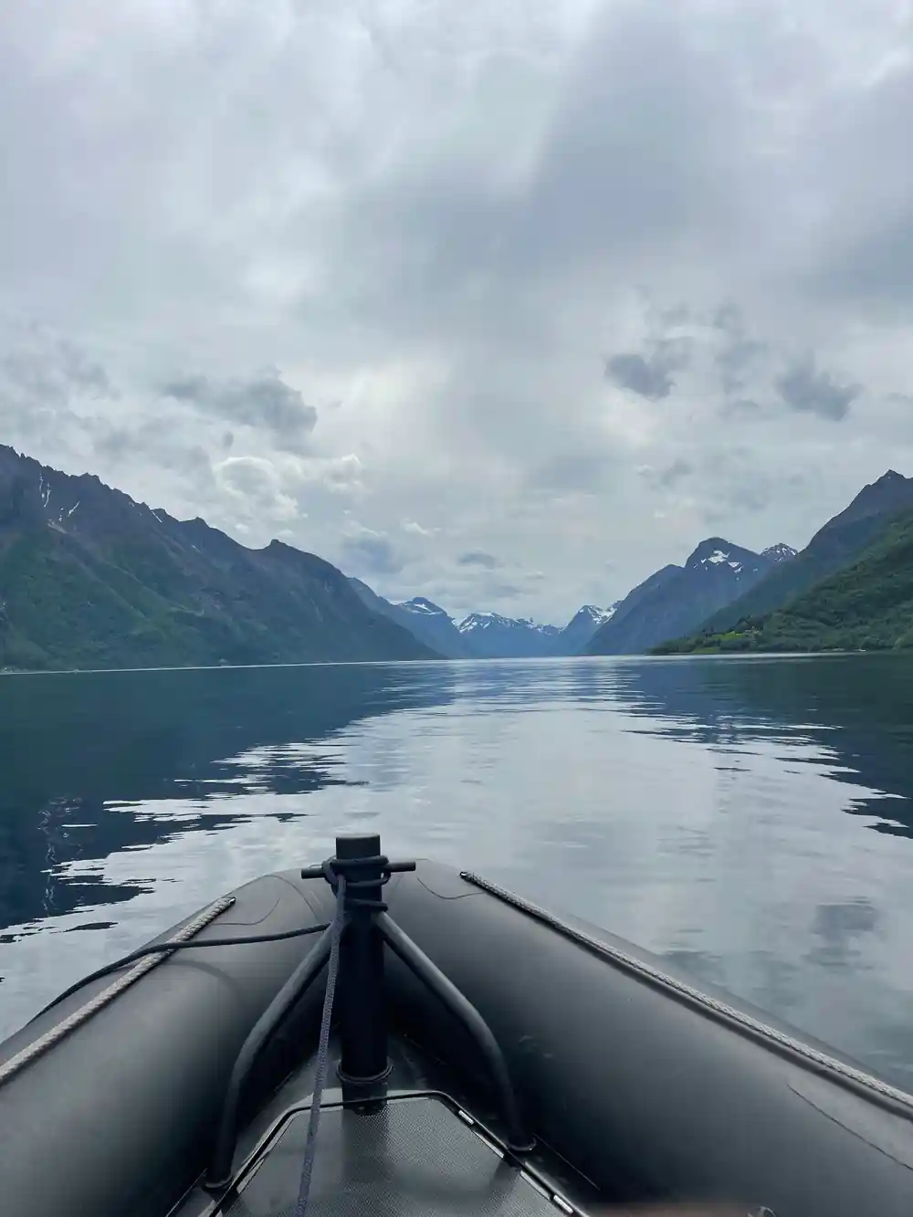 Speedboat bow pointed toward green-forested mountains